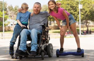 Disabled man in powerchair with two children