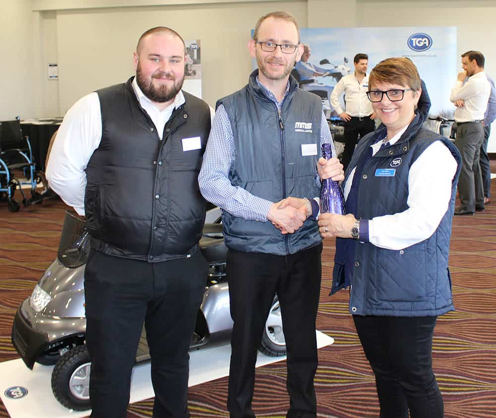 Julie Stokes, TGA Trade Coordinator/Area Sales Manager for Scotland & Ireland (right) presents David Delaney (left) and Tim Cronin (centre), MMS Medical Product Specialists, with a bottle of champagne in recognition of winning TGA Dealer of the Quarter.