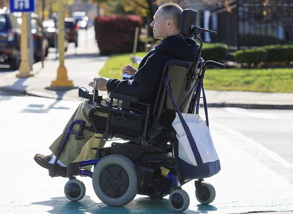 Man in powered wheelchair crossing the road