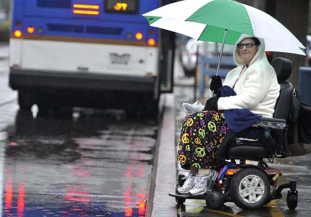 Mobility powerchair in the rain with user holding umbrella
