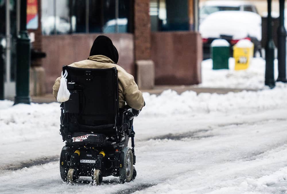 A mobility powerchair user riding in the snow