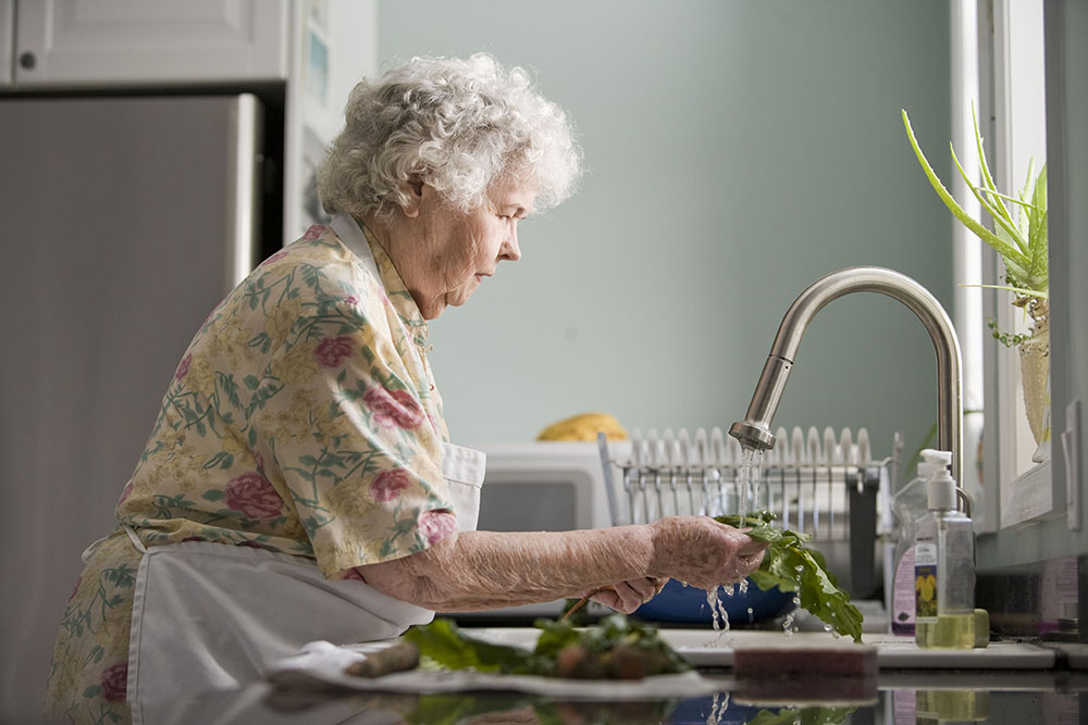 elderly woman at home washing up