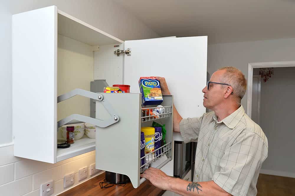 Habinteg Housing Association Rawcliffe Grove Hull. Resident Geoffrey Bone using adapted cupboard in the kitchen.