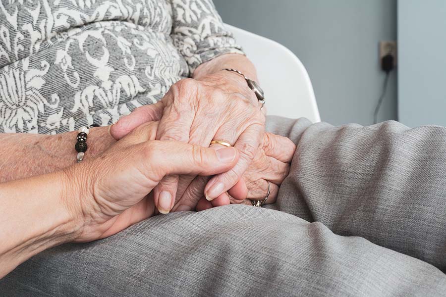 elderly person holding hands at home