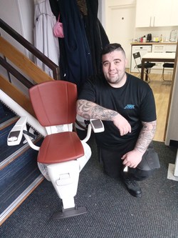 Engineer Scott Thomas with a stairlift helped to fix for the charity SNOOSC